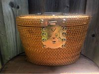 Front view of the woven picnic basket showing the owl-shaped metal lock on the lid.