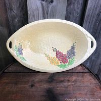 Front and angled view of oval ceramic serving tray showing floral decoration and integrated side handles