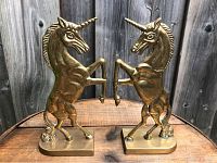 Front-facing view showing both brass unicorn statues standing opposite each other in rearing pose.