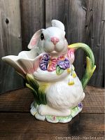 Front side view of the ceramic bunny creamer showing the bunny face with hand-painted flowers and tulip-shaped spout.