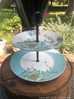 Full view of the two-tier pastry tray showing the floral design on fine china plates and metal handle.