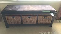 Front view of the wooden storage bench showing cushion and three wicker baskets.