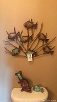 Metal wall art with seven fish attached to branch-like stems