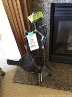 Fireplace tool set and stand made of wrought iron with wooden handled tools.