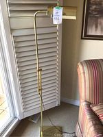 Full view of the vintage brass floor lamp positioned near a window and chair.