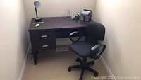 Wooden desk with two drawers and office chair beside it