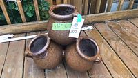 Three brown ceramic strawberry pots arranged with one larger pot on top and two smaller pots below on a wooden deck background. The largest pot has a green label stating 16 inch width and a tag with '200'.