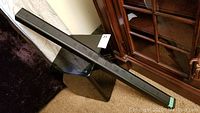 Full length Samsung soundbar leaning against furniture in room