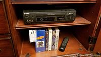 Sony SLV-N500 VHS Player and VHS tapes below it, including an unopened Seinfeld complete series tape set with other music tapes and a remote control.