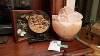 Overview of Himalayan salt lamp, cork carving, and framed dried flowers and butterflies on wooden surface.