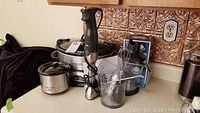 Photo showing Crock-Pot slow cooker and Little Dipper warmer side by side with Breville immersion blender and accessories on kitchen counter