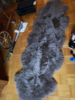 Full view of the gray double sheepskin rug laid flat on hardwood floor, showing size and shape.