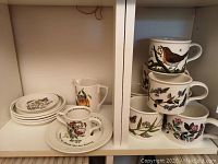 Six large mugs and various plates and dishes on shelf