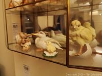 Displays white duck, three chick figurines, and brown hare in the showcase from the side view.