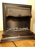 Front view of black metal electric fireplace with faux coal logs