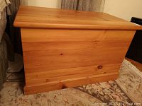 Front view of the pine chest showing the wood grain and knots, with some scratches visible.