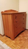 Side view of four drawer pine dresser showing scalloped base and side panels with visible wear.