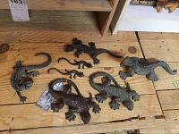 All seven cast iron lizards arranged on wooden floor