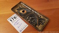Top view of rectangular ceramic tray with peacock feather design and tag showing size and brand.