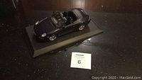 Top and side angle view of the black Maisto Porsche Carrera S model car on plastic base showing overall condition and details.