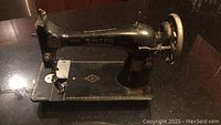 Full side view of the black Singer sewing machine showing machine shape and gold detailing.