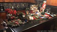 Photo showing various Christmas decorations spread out on a kitchen counter including wreaths, poinsettia plants, figurines, and the Nutcracker stand-up light.