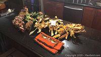 Photo showing a black counter with various autumn-themed decorations including wreaths, foliage, corn bundles, and a small orange cloth item.