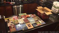 Books arranged on kitchen countertop showing a wide selection of titles including some about birds, sailing, and regional guides.