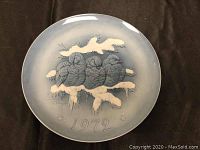Full front view of the vintage 1972 Hutschenreuther blue-gray porcelain wall plate featuring four birds on a snow-covered branch, artist signed.