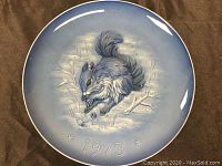 Front view of the signed Hutschenreuther wall plate depicting a squirrel in a winter scene with the year 1973 embossed.