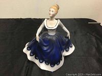 Front view of Royal Doulton Lisa figurine in blue and white dress, seated pose.
