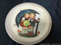 Photo showing detailed image of two children under umbrella on plate surface to illustrate condition and design.