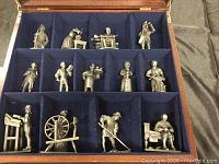Overview of all 12 pewter figurines in the mahogany box with blue felt lining, showing various colonial American figures and occupations.