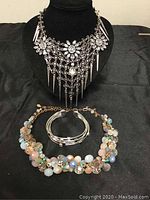 Overall view of 2 necklaces and cuff bracelet displayed on black velvet stands showing lot contents clearly.