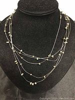 Five strand pearl and silver necklace shown on black display bust, highlighting layering and pearl spacing.