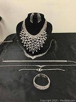 Full set of vintage costume jewelry laid out on black cloth, showing all necklaces, bracelets, and earrings.