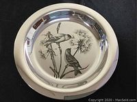 Front view of circular sterling silver plate with bird etching
