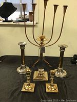 Full lot showing R. Isart candlestick, two pairs of candlesticks, and a candelabra on black cloth