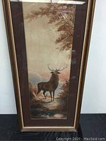 Full view of framed watercolour painting showing the stag in landscape with muted color palette and wood frame.