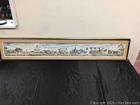 Full view of the framed panoramic artwork placed against wall showing entire length and frame condition
