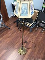 Full view of brass floor lamp with nautical hexagonal shade in room with wooden floor