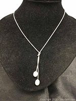 Front view of necklace displayed on a black velvet bust showing silver chain with pearls hanging from loop knot detail.