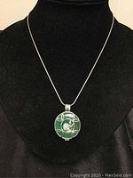 Full view of necklace with green pendant on black display bust.