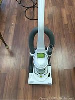 Front and top view of the upright vacuum showing the handle, hose, and power indicator.