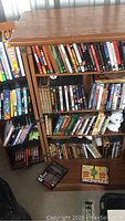Front view showing DVDs arranged on shelves inside cabinet and some DVDs on the floor nearby