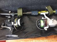 Fishing rod and two attached spinning reels laying inside a case; used condition with some wear