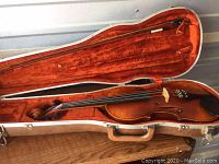 Violin and bow inside open case showing overall condition