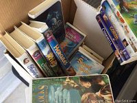 Box with Disney VHS tapes arranged showing front covers including Hercules, Sleeping Beauty, and The Secret of the Sword