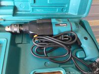 Makita corded electric drill in carrying case, showing drill and coiled power cord.