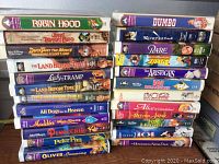 Box of assorted Disney VHS tapes stacked vertically, showing front spines with titles and artwork.